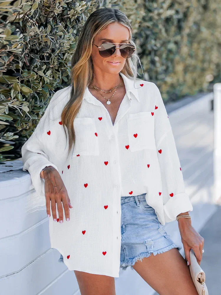 Women's white cotton crinkle shirt with red heart embroidery, long sleeves, casual loose fit, paired with denim shorts, spring fashion 2023.