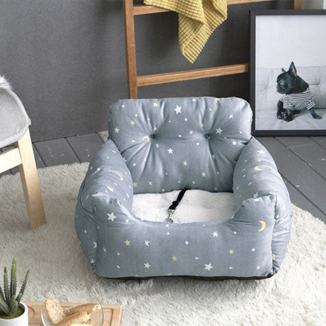 Cozy dog car seat with star and moon pattern, featuring a safety strap, on a plush rug. Ideal for pet travel comfort and safety.