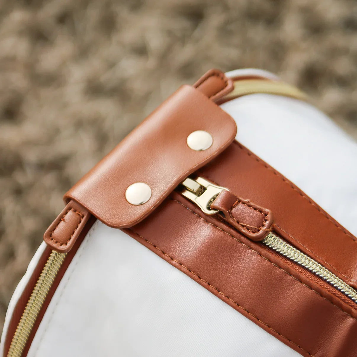 Close-up of a stylish folding duffel bag with brown leather accents and a gold zipper, perfect for travel and storage. Durable and fashionable design.