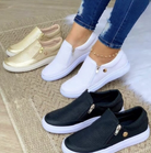 Women's casual slip-on sneakers in gold, white, and black on a woven rug. Breathable, flat vulcanized shoes ideal for spring and summer fashion.