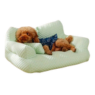 Cute brown poodle lounging on a light green quilted dog sofa, wearing a blue bandana. Cozy pet furniture, comfortable dog bed, stylish pet accessory.