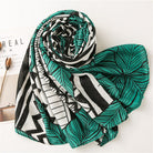 Green and black leaf-patterned scarf on white background, featuring bold geometric designs. Fashion accessory, stylish women's scarf, modern print.