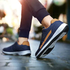 Casual navy blue and brown sneakers with white soles on a cobblestone street, perfect for urban fashion and comfortable walking shoes.