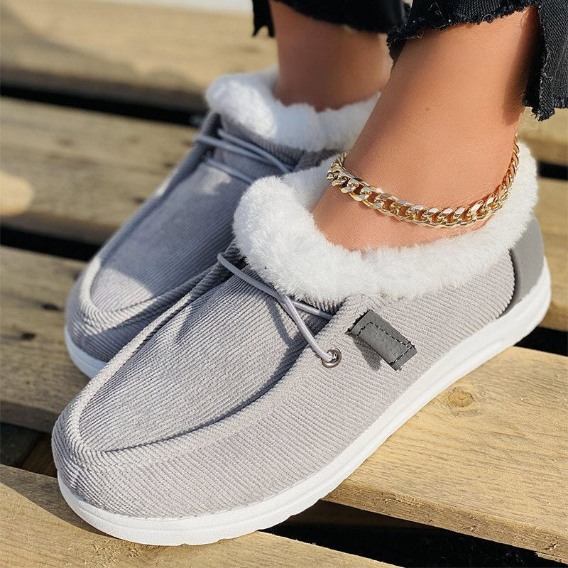 Women's gray slip-on shoes with white faux fur lining, featuring a casual design and gold anklet. Perfect for cozy winter fashion and comfort.