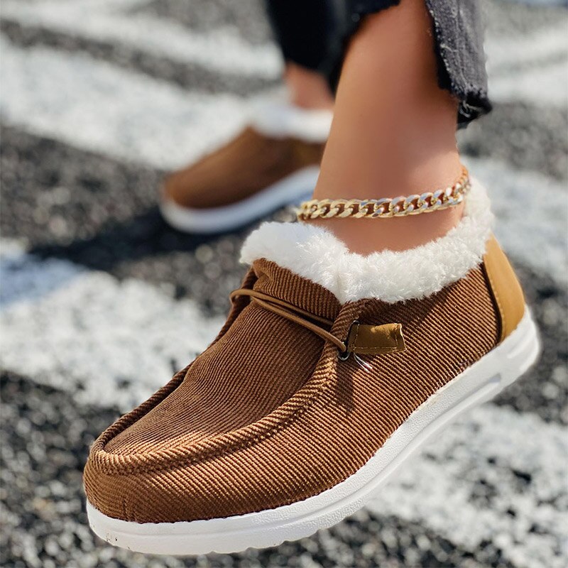 Brown corduroy slip-on shoes with white fur lining, worn with a gold anklet. Casual footwear for women, perfect for fall fashion trends.