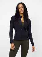 Black zip-up blouse with long sleeves, worn by a woman, paired with olive green leggings. Fashionable activewear, perfect for workouts or casual wear.