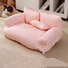 Pink textured pet sofa bed on beige carpet, featuring plush cushions and armrests, ideal for small dogs or cats. Cozy pet furniture for home decor.