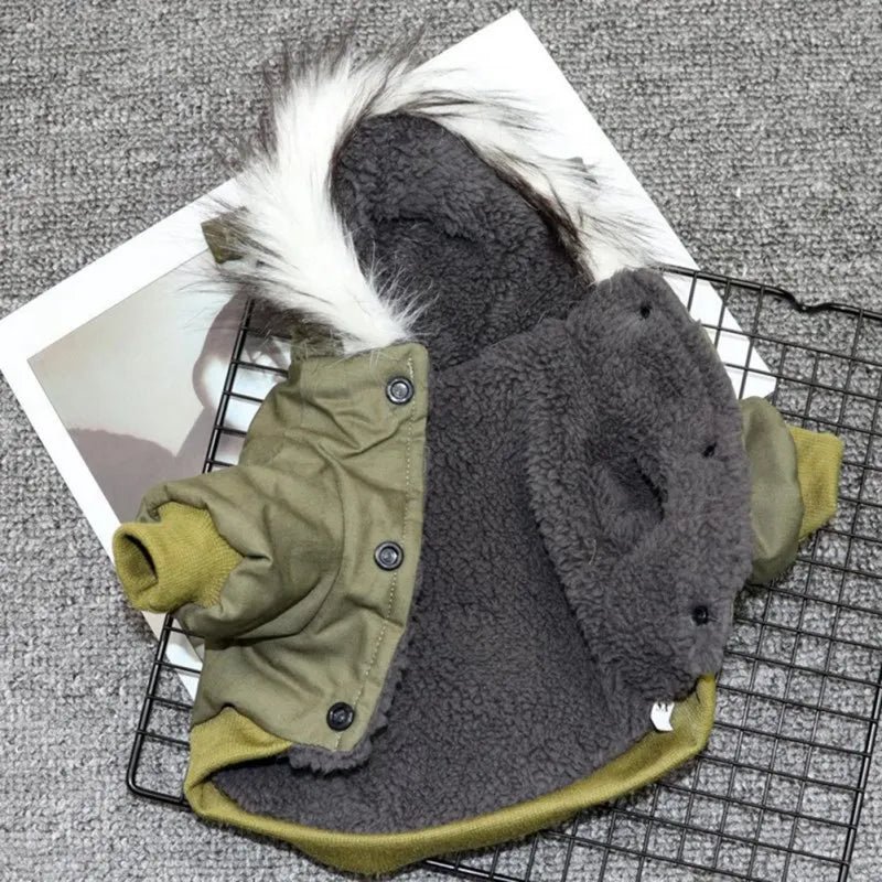 Olive green dog winter coat with faux fur hood, fleece lining, and button closure on a gray textured background. Warm pet apparel for cold weather.