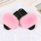 Pink fluffy fur slippers on black soles, placed on a white surface. Cozy, stylish footwear ideal for indoor comfort and fashion.