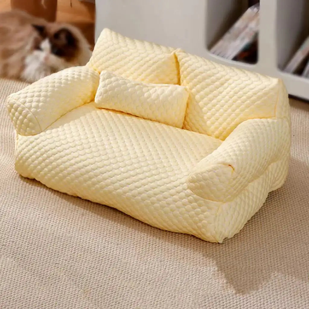 Yellow plush pet sofa on beige carpet, featuring a textured design and matching pillow, ideal for small pets. Cozy pet furniture, stylish home decor.