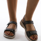 Women's black leather sandals with adjustable straps, cushioned sole, and open-toe design. Perfect for summer fashion and comfortable walking.