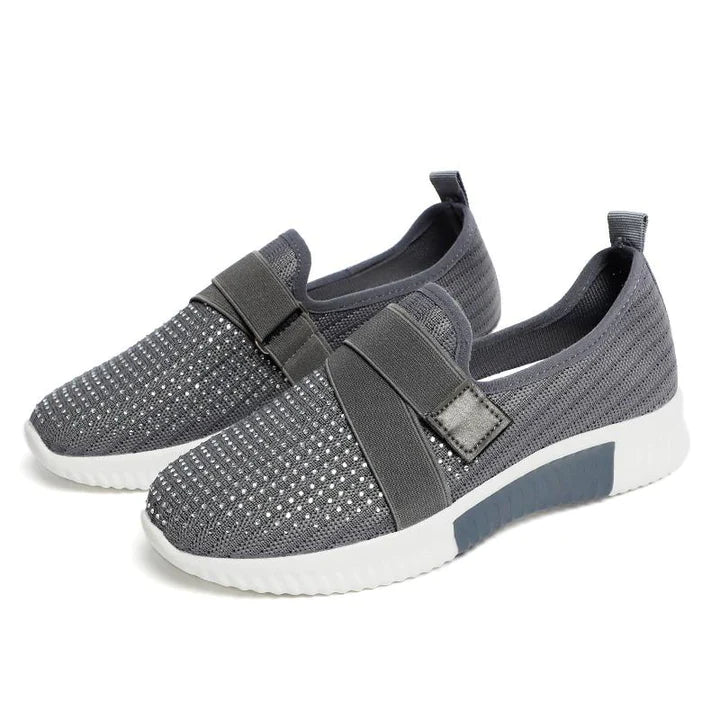 Gray slip-on sneakers with Velcro strap, breathable mesh design, and white sole. Ideal for improved walking posture and casual wear.