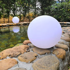 LED Glimmer Sphere on stone path by pond, outdoor decorative lighting, modern garden decor, energy-efficient, waterproof, ambient illumination.