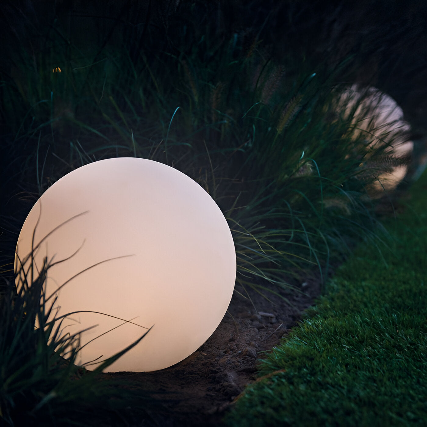 LED outdoor decorative sphere light in garden setting, glowing softly among grass. Perfect for landscape lighting, energy-efficient garden decor.