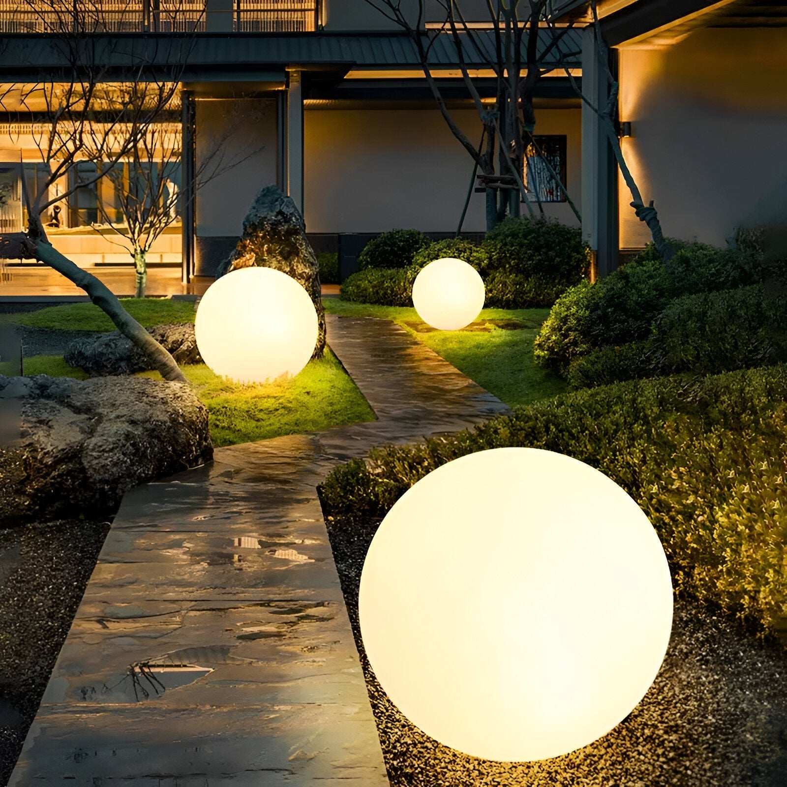 Glowing LED outdoor spheres illuminate a modern garden path at night, enhancing landscape design with ambient lighting. Perfect for decorative garden lighting.