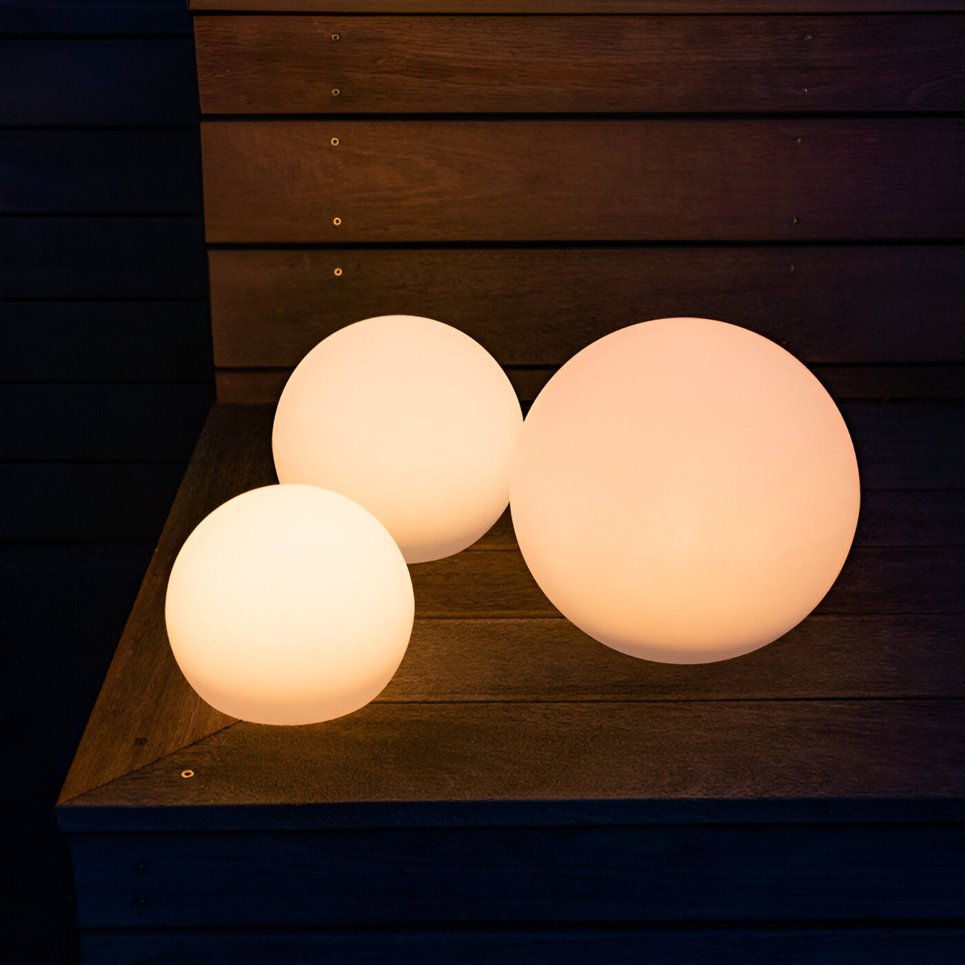 Glowing LED sphere lights on wooden steps, outdoor decorative lighting, energy-efficient garden decor, warm ambiance, modern patio illumination.