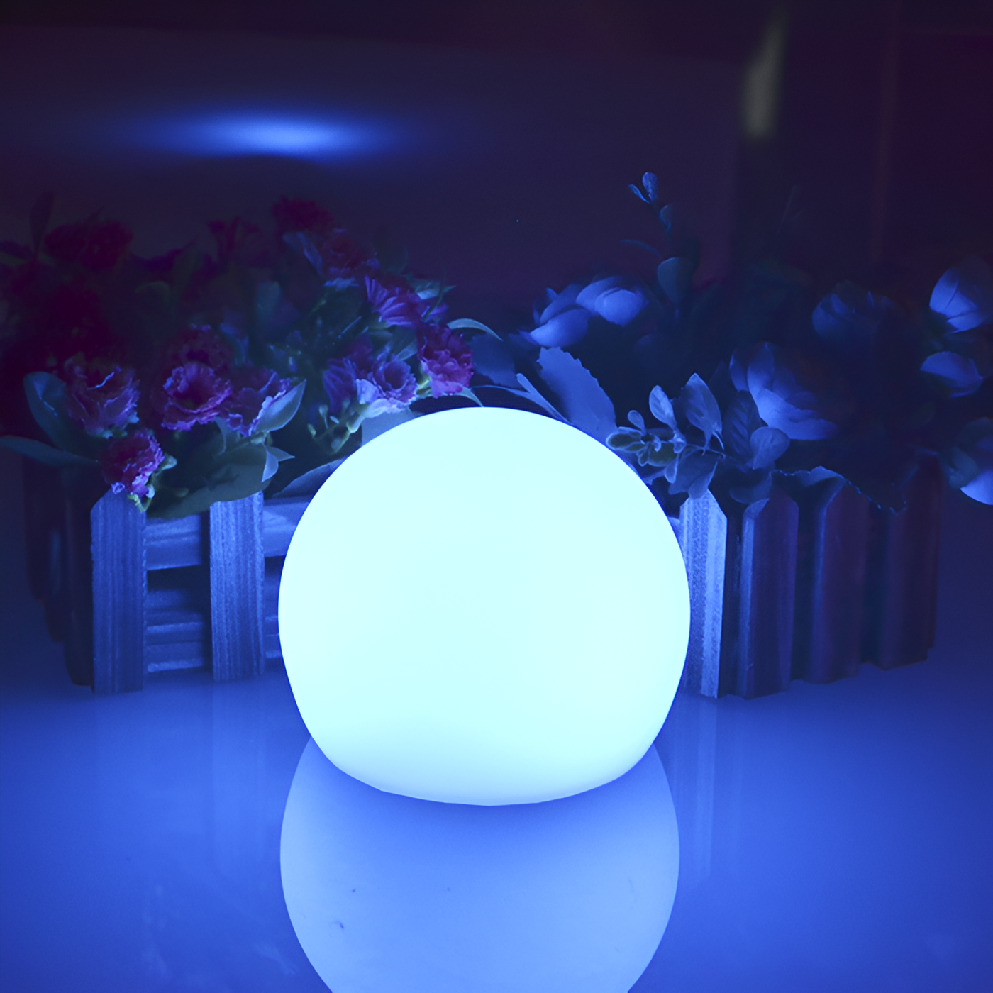 Glowing LED sphere light for outdoor decor, surrounded by vibrant flowers in wooden planters, creating a serene ambiance. Perfect for garden illumination.