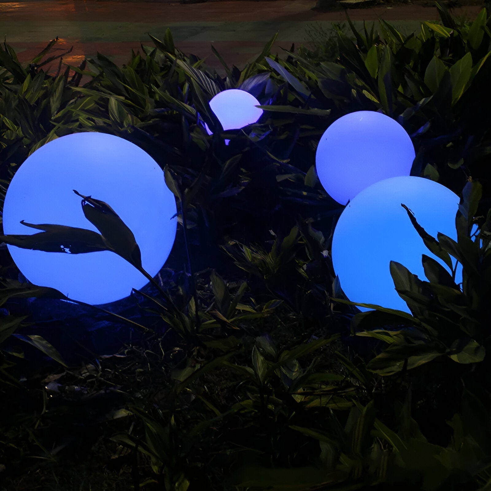 Glowing LED spheres in a garden setting, featuring vibrant blue and purple hues. Perfect for outdoor decoration, enhancing nighttime ambiance.