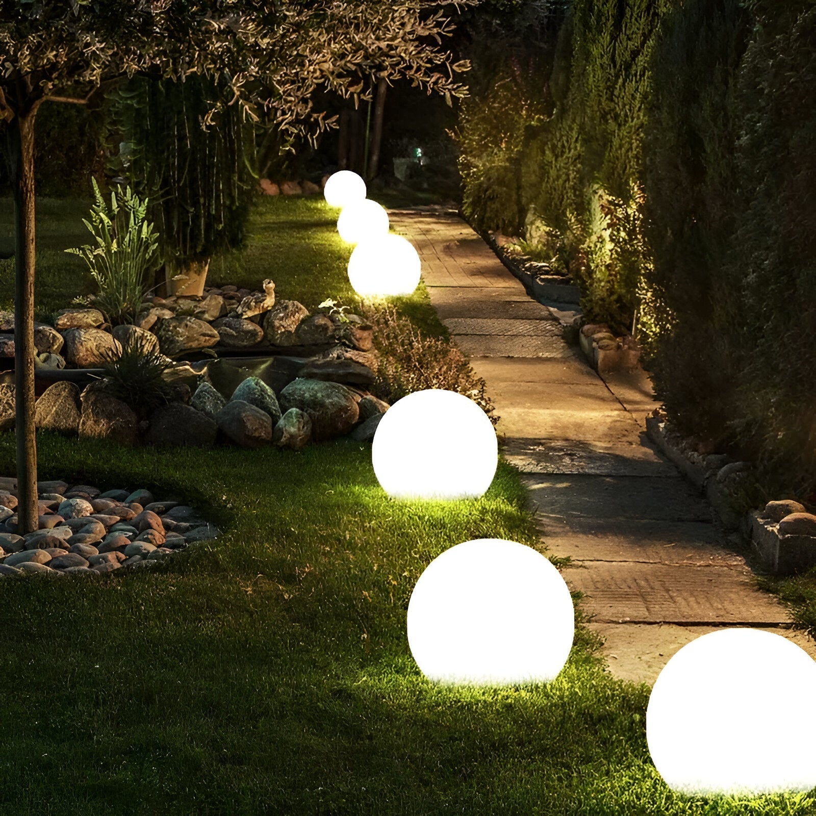 Glowing LED sphere lights illuminate a garden pathway at night, creating a serene outdoor ambiance. Perfect for landscape lighting and garden decor.