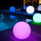 Colorful LED sphere lights illuminating a modern outdoor patio by a pool at night, featuring vibrant pink, blue, and green hues for stylish decor.