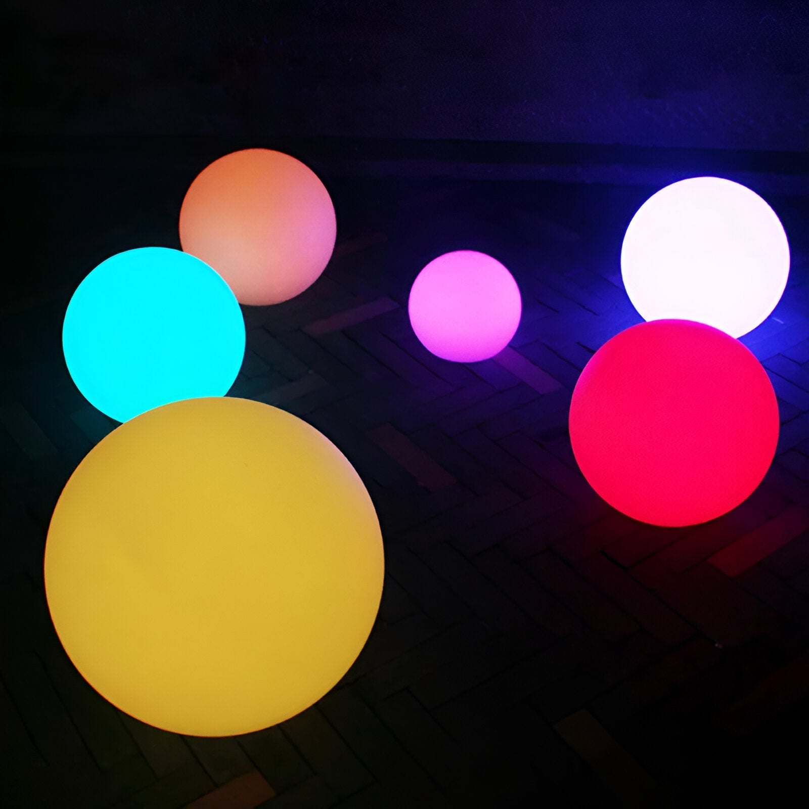 Colorful LED spheres glowing in the dark, featuring vibrant hues of yellow, blue, pink, and red. Perfect for outdoor decoration and ambient lighting.