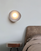 Modern pebble-shaped wall light illuminating a bedroom, featuring soft ambient lighting. Ideal for contemporary home decor and interior design.