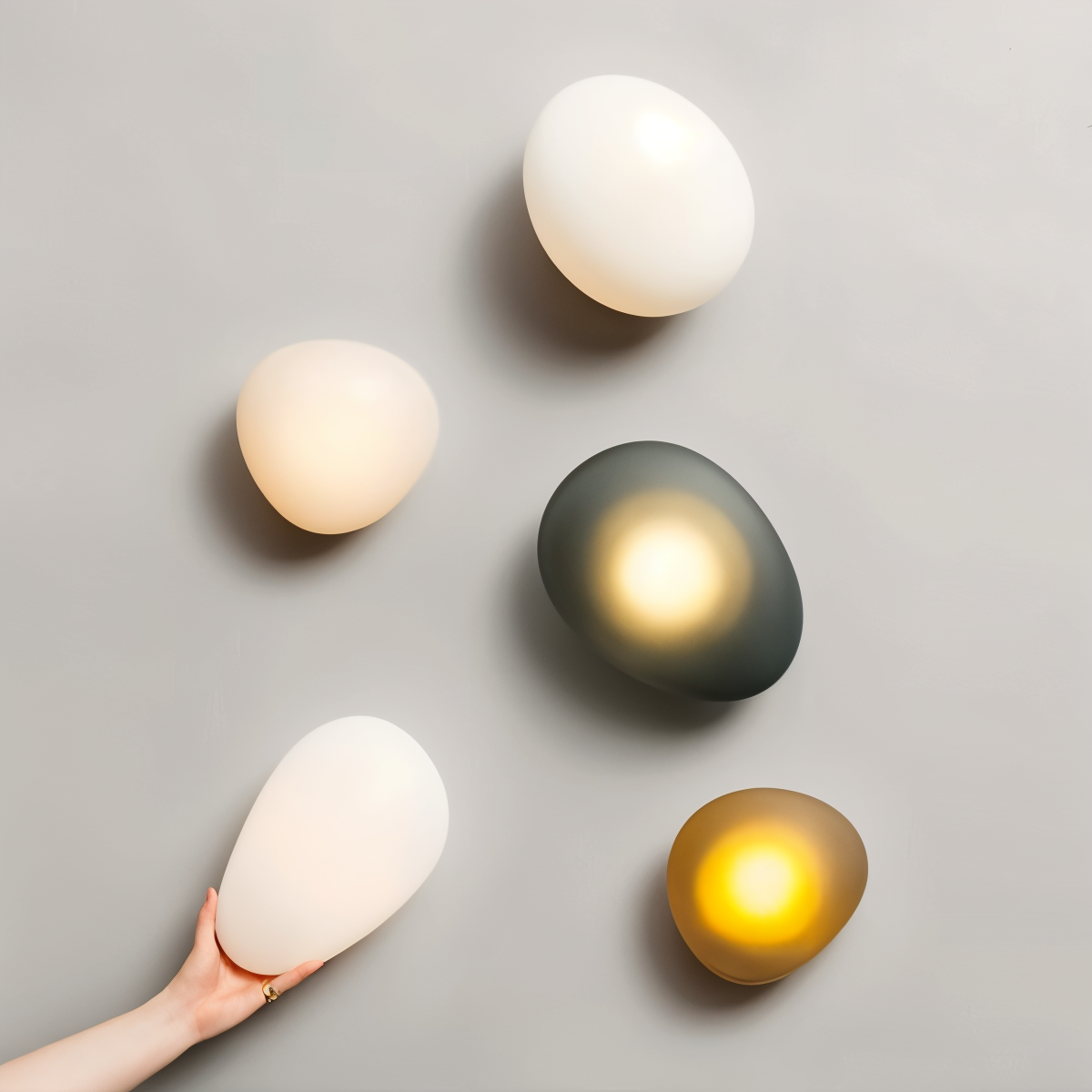 Modern pebble-shaped wall lights in various colors on a gray background, showcasing contemporary home lighting design and interior decor trends.