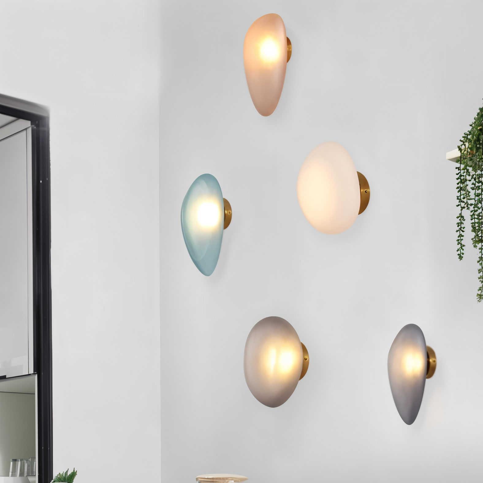 Modern pebble-shaped wall lights in various hues on a white wall, featuring minimalist design and ambient lighting, perfect for contemporary home decor.