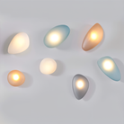 Modern pebble-shaped wall lights in various colors and sizes, featuring soft ambient LED lighting. Perfect for contemporary home decor and interior design.