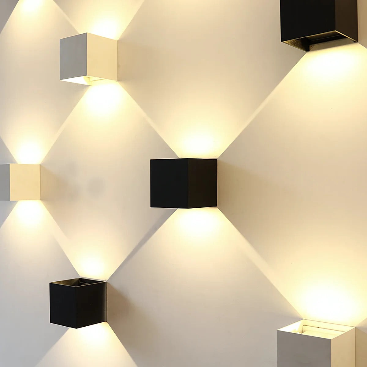 Modern wall lights in black and white cube designs, illuminating a room with warm LED lighting. Stylish home decor, contemporary lighting fixtures.