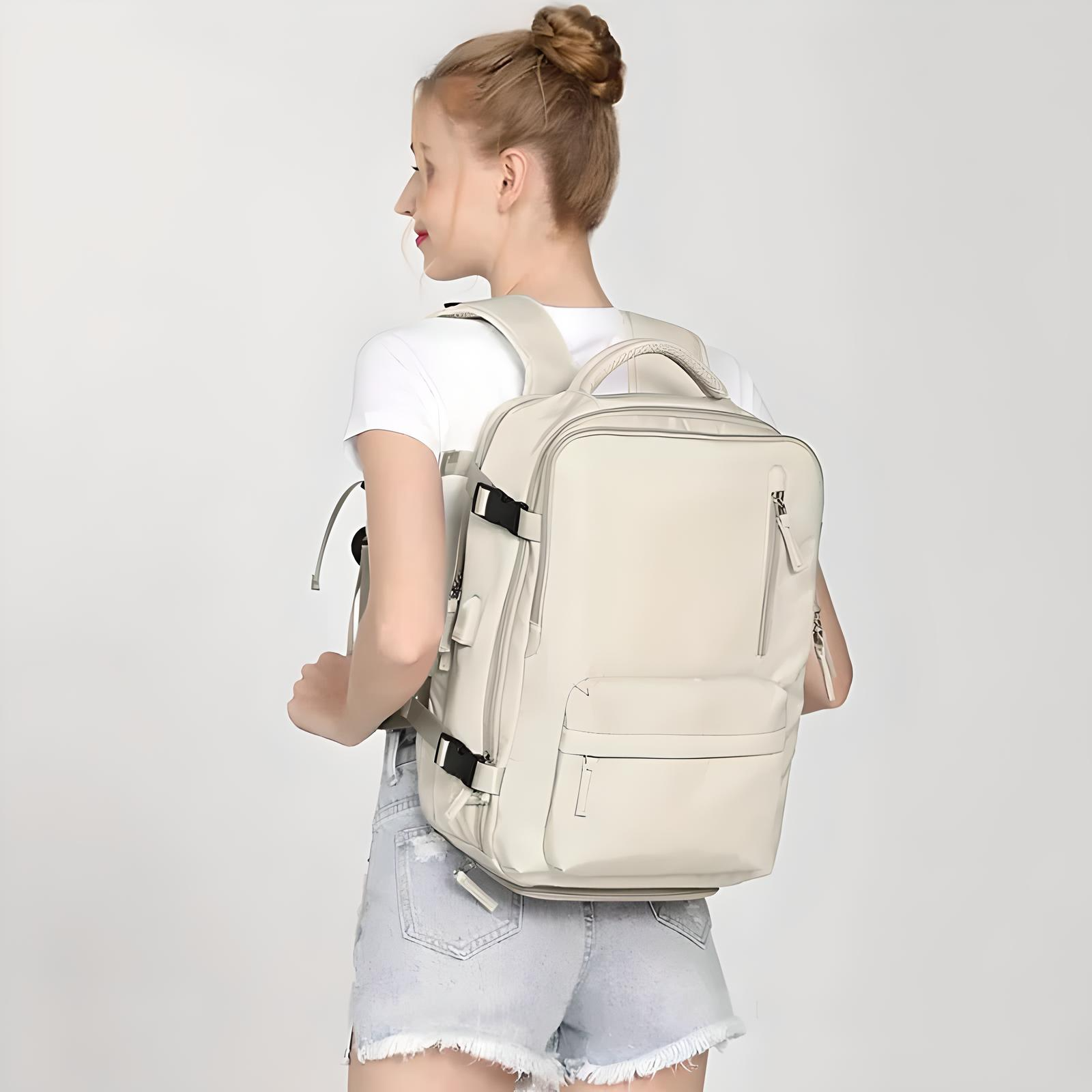 Woman wearing a stylish beige backpack with multiple compartments, adjustable straps, and a sleek design. Perfect for travel, school, or work essentials.