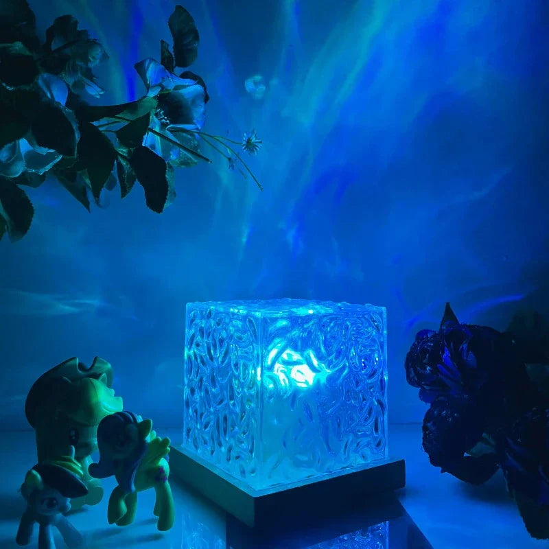 Illuminated glass block lamp with intricate patterns on a wooden base, emitting a blue glow. Perfect for ambient lighting and home decor.