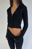 Woman wearing a black ribbed knit zip-up hoodie and matching pants, showcasing trendy fall fashion. Stylish, comfortable, and chic outfit.