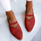 Red woven leather women's slip-on shoes with pointed toes, worn with white pants. Stylish, comfortable footwear for casual or formal occasions.