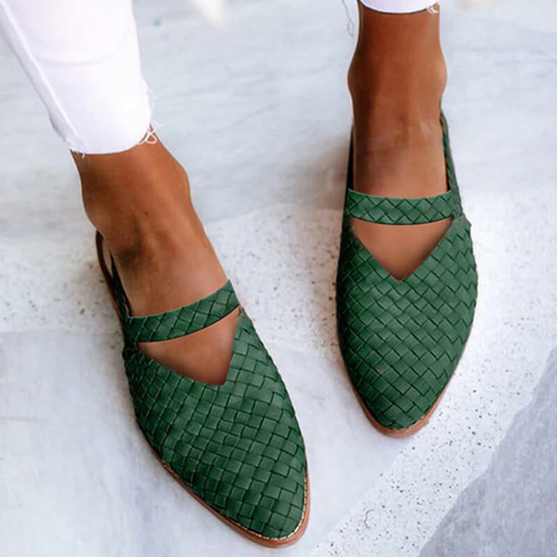 Green woven leather women's slippers with pointed toes, worn with white pants. Stylish, comfortable footwear for casual and formal occasions.