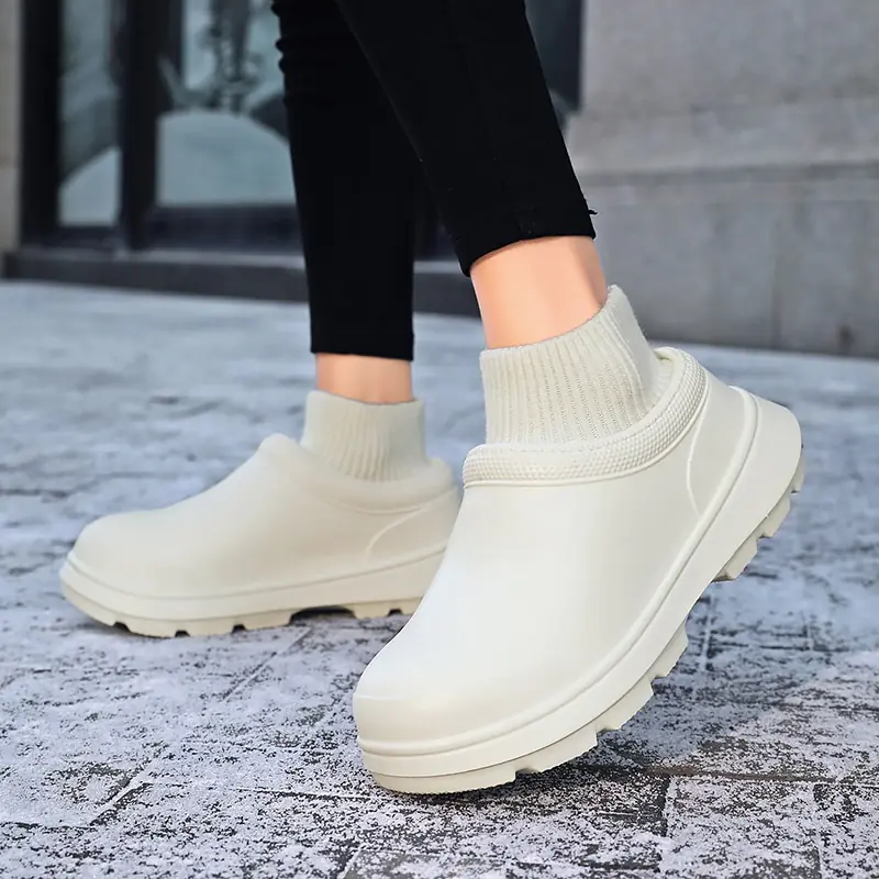 Stylish beige slip-on shoes with ribbed sock design, worn outdoors on a textured pavement. Trendy footwear for casual fashion and comfort.