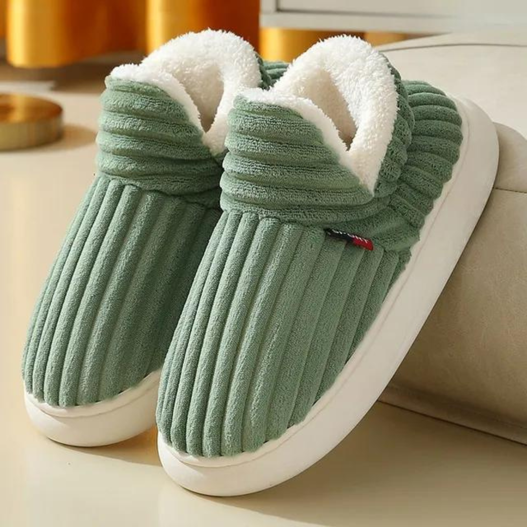 Green ribbed slippers with plush white lining on a beige surface, cozy indoor footwear, perfect for winter warmth and comfort.