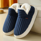 Cozy blue ribbed slippers with plush white lining on a beige surface, perfect for indoor comfort. Ideal winter footwear, stylish and warm.