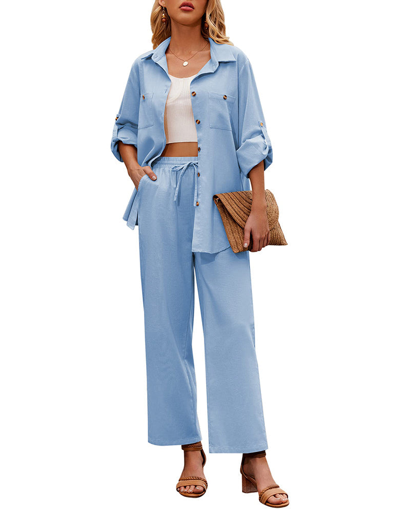 Woman in light blue two-piece outfit with button-up shirt and wide-leg pants, holding a woven clutch. Fashionable summer attire, casual chic style.