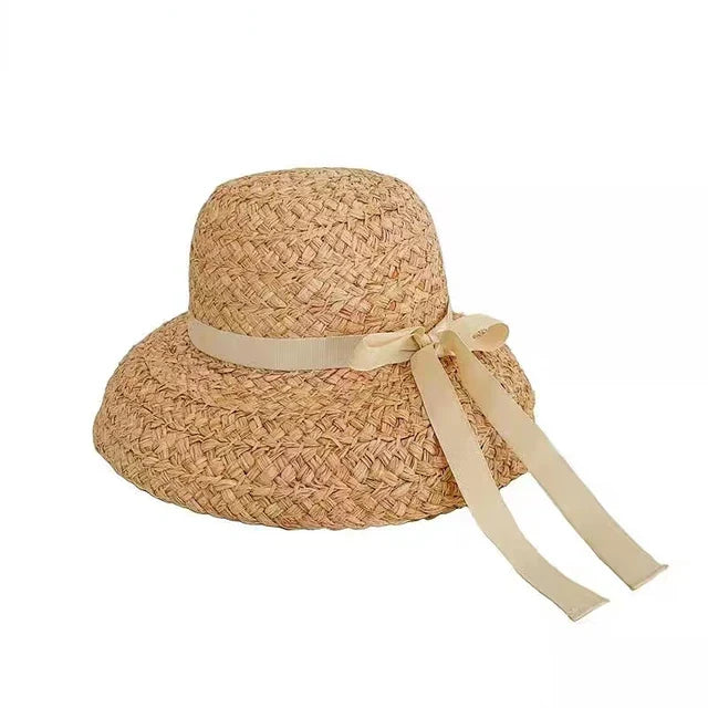 Wide-brimmed raffia straw hat with flat top, beige ribbon bow. Perfect for summer beach vacations. Women's UV sun protection hat.