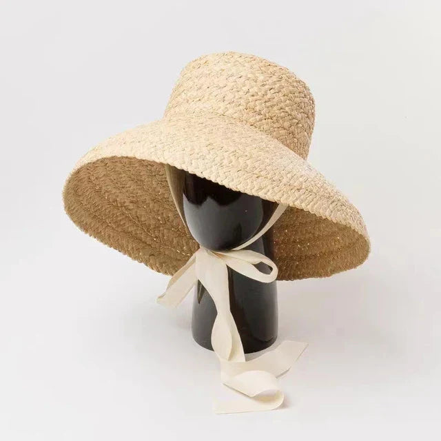 Wide-brimmed raffia straw hat with flat top, featuring a white ribbon tie. Perfect for women's summer beach vacations. UV protection sun hat.