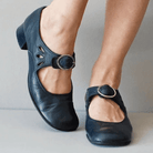 Black leather Mary Jane shoes with buckle strap, low heel, and cutout design. Women's comfortable footwear, stylish casual shoes for everyday wear.