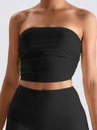 Woman wearing a black strapless ribbed crop top and matching high-waisted skirt, showcasing trendy summer fashion.