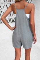 Woman wearing a gray sleeveless romper with white tank top, standing against a geometric patterned wall. Casual summer fashion, back view.