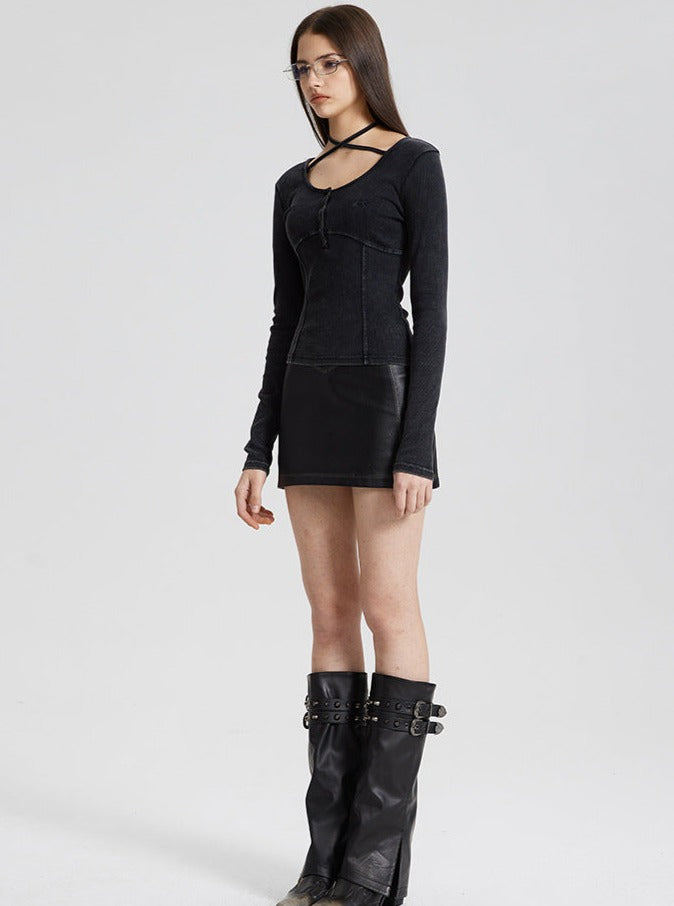 Woman in black gothic dress with long sleeves, wearing knee-high leather boots and glasses, standing against a plain background. Fashion, edgy style.