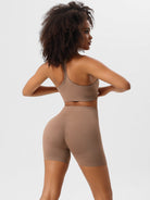 Woman in seamless brown activewear set, featuring a sports bra and high-waisted shorts, ideal for yoga and fitness. Comfortable, stylish workout outfit.