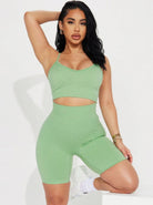 Woman in green workout set, featuring a crop top and high-waisted shorts, posing confidently. Fitness fashion, activewear, stylish gym outfit.
