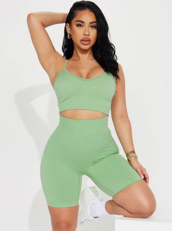 Woman in green workout set, featuring a crop top and high-waisted shorts, posing confidently. Fitness fashion, activewear, stylish gym outfit.