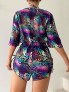 Woman wearing a vibrant tropical print romper with colorful palm leaf patterns, showcasing summer fashion trends.