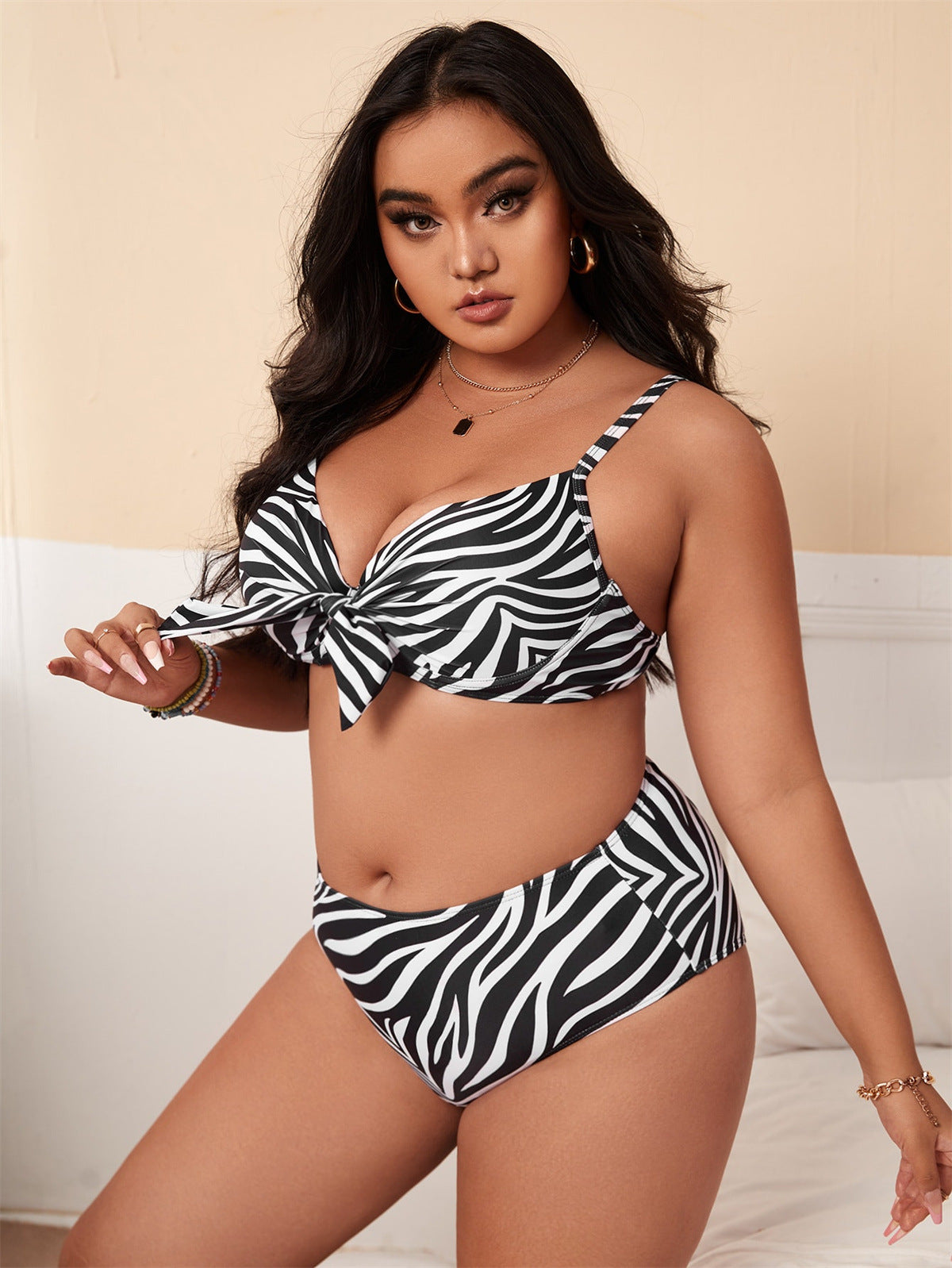 Zebra print bikini set featuring a bow tie front, worn by a model with long dark hair. Trendy swimwear fashion for summer beachwear.